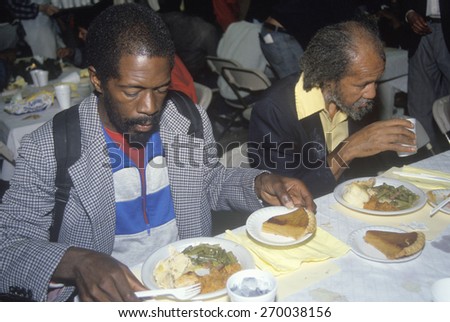 Two black men eating Christmas dinner at homeless shelter, Los Angeles, California