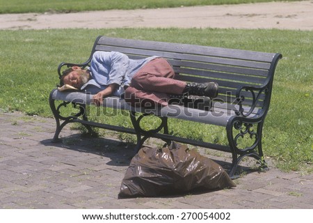 Homeless man sleeping on a park bench, Los Angeles, California
