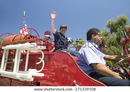 Fire truck and firefighters with dog make their way down main street during a Fourth of July parade in Ojai, CA