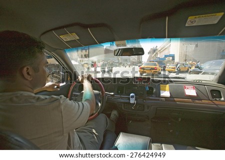 Interior view of taxi cab and driver steering through New York City, Manhattan streets, New York