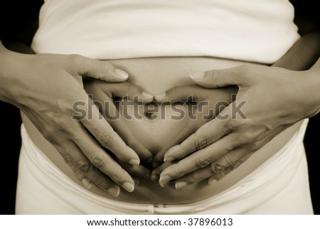 Womans\' hands over childs\' hands on top of pregnant womans\' belly