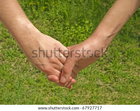 Two hands over green nature background. Love and friendship concept