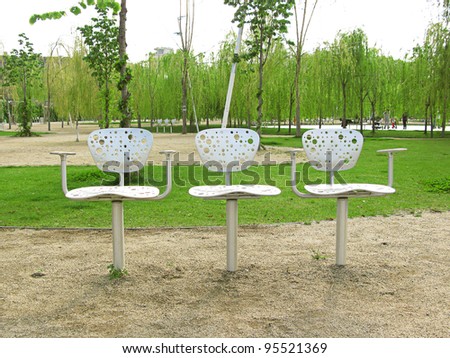 Three metallic design chairs in a park in Barcelona