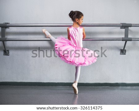 beautiful little ballerina in pink dress in dance class