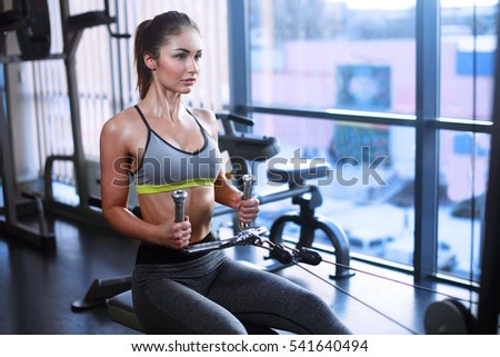 Athletic young woman works out on training apparatus in gym class