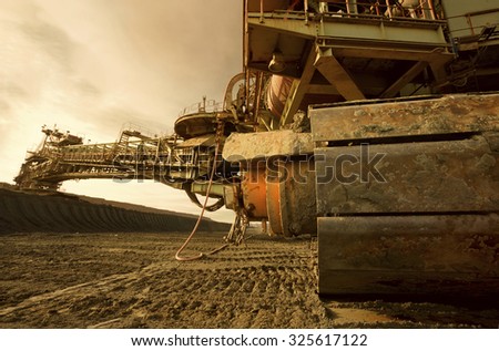 One side of huge mining drill machine photographed from a ground with wide angle lens. Dramatic and colorful sky in background.