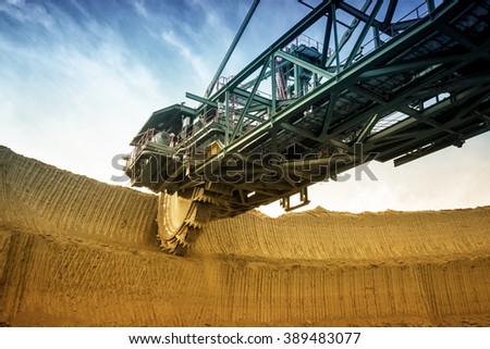 One side of huge coal mining digger machine photographed from a ground with wide angle lens. Dramatic and colorful sky in background.