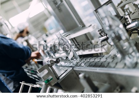 Robotic factory line for processing and bottling of pure spring water into canisters and bottles. Selective focus. Short depth of field.