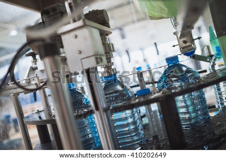 Robotic factory line for processing and bottling of pure spring water into canisters and bottles. Selective focus. Short depth of field.