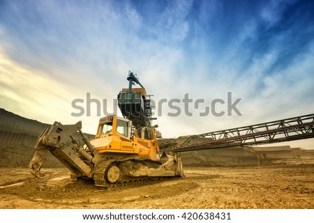 One side of huge mining drill machine connected to transportation facility. Photographed from a ground with wide angle lens. Dramatic and colorful sky in background.