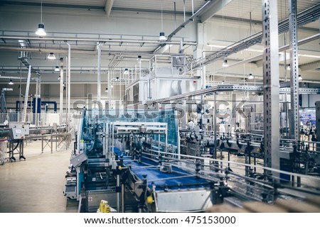 Industrial interiors. Robotic factory line for processing and quality control of pure spring water bottled into canisters. Low light and small amount of noise visible.