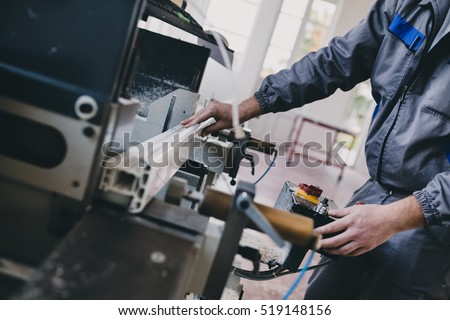 Manual worker cutting aluminum and PVC profiles. Manufacturing jobs. Selective focus. Factory for aluminum and PVC windows and doors production.