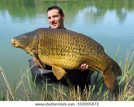 Happy  fisherman holding a beautiful common carp