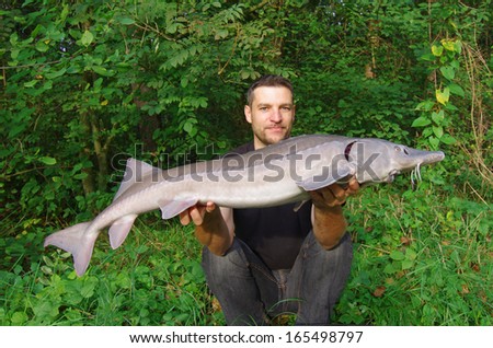 Happy fisherman holding a sturgeon