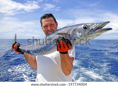 Deep sea fishing. Fisherman holding a wahoo fish.