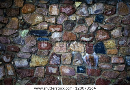 Wet concrete wall with stones of various colors and forms