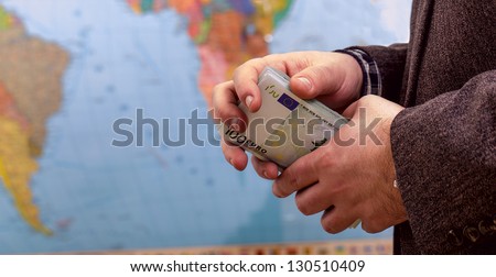 male hands in his jacket holding a pack of euro on the world political map