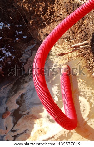 red tube pumps out the water drains in the earthen pit