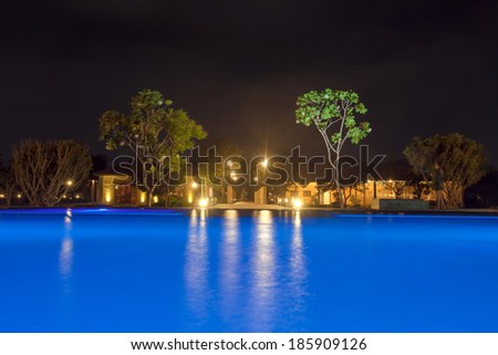 swimming  pool with blue water on the shore of the Indian Ocean Sri Lanka night. Around trees and a bridge over the river