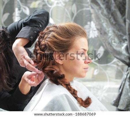girl make French braid hairstyle in salon