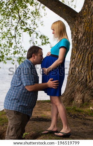Man kissing pregnant woman\'s belly. Young couple on the nature