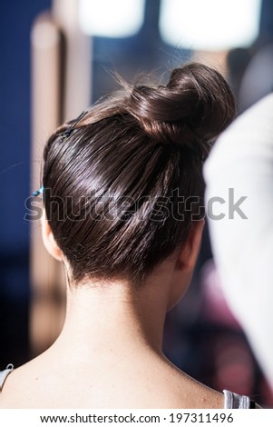 Hair stylist creates on the girl's head. Back view