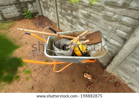 wheelbarrow with building and garden supplies in the yard