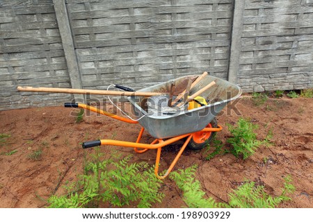 wheelbarrow with building and garden supplies in the yard