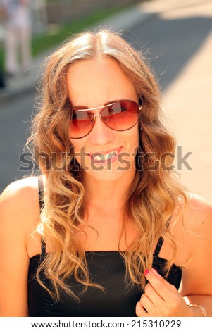 beautiful girl with long hair in sunglasses smiling at the camera