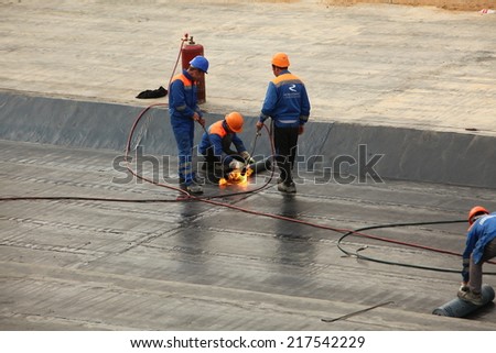 workers in hard hats are placed on concrete roofing material. Belarus,Minsk,September,14,2014