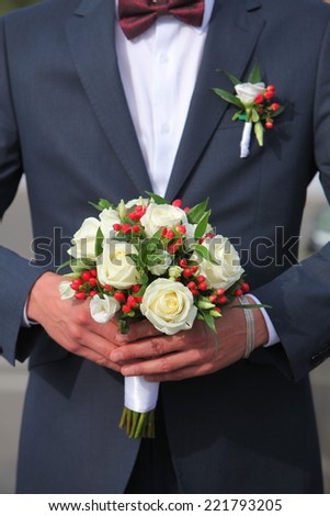 bridegroom in festive costume. Wedding bouquet of roses holding a man\'s hand