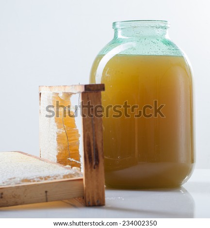 Honey comb in a wooden frame. Honey in a glass three-liter jar.