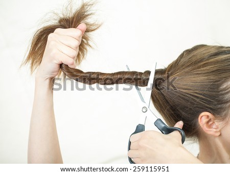 woman cuts her hair with scissors