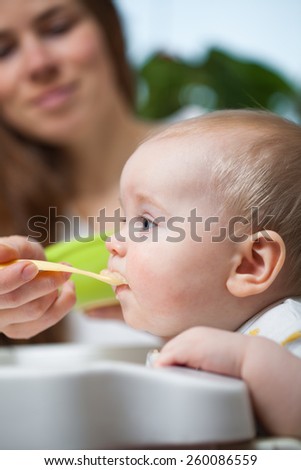 Mom is feeding baby with a spoon