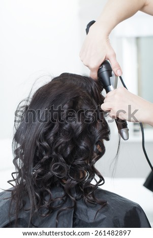 the creation of women\'s hairstyles in the salon stylist twisting around