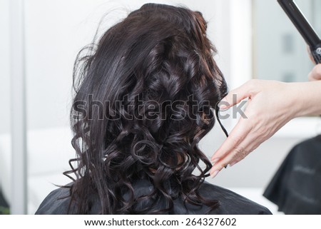 stylist hairdresser creates feminine hairdo in the beauty salon. black hair