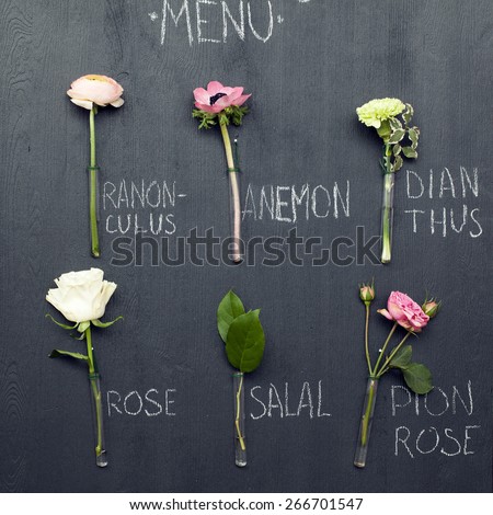 six natural fresh flowers in a test tube with water piece on a blackboard with chalk written name