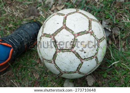 old shabby soccer ball on the grass.foot player in football boots sports equipment.