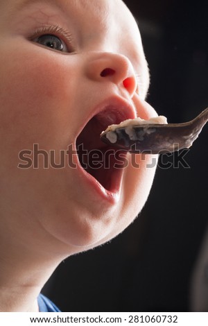 baby opened his mouth wide to eat cereal from a spoon