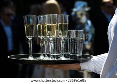 a glass of champagne on a tray in hand Waiter