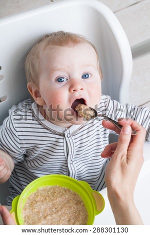 Feeding baby cereal in a spoon mouth wide open child