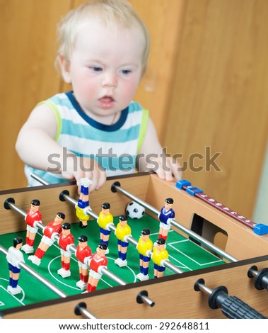 Kid playing table football with the ball sitting on the floor