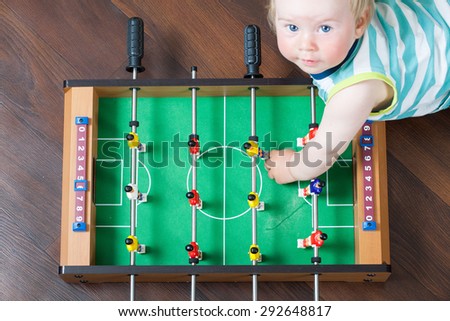 Kid playing table football with the ball sitting on the floor