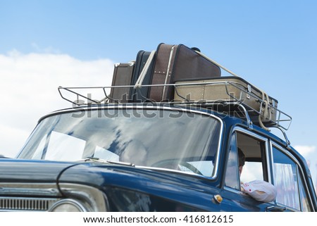 Vintage suitcases on the roof of the trunk of a car.