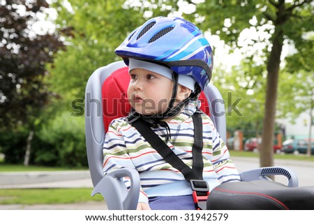 child sitting by bicycle in crash helmet