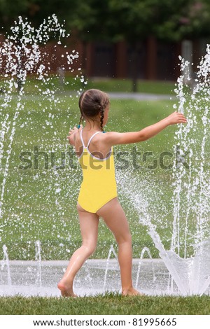 A young girl having fun on a splash pad.