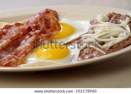 breakfast eggs / Two sunny side up eggs served with bacon strips  beans and hash brown.