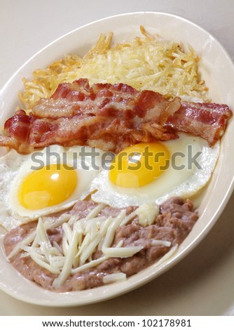 breakfast eggs / Two sunny side up eggs served with bacon strips  beans and hash brown.