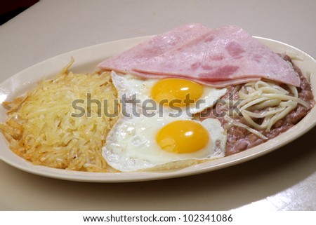 breakfast eggs / Two sunny side up eggs served with ham,  beans, and hash brown.