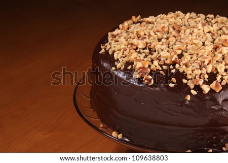 Home made Chocolate cake topped with chopped pecans, on a cake base. Made by a pastry chef. / Chocolate Cake